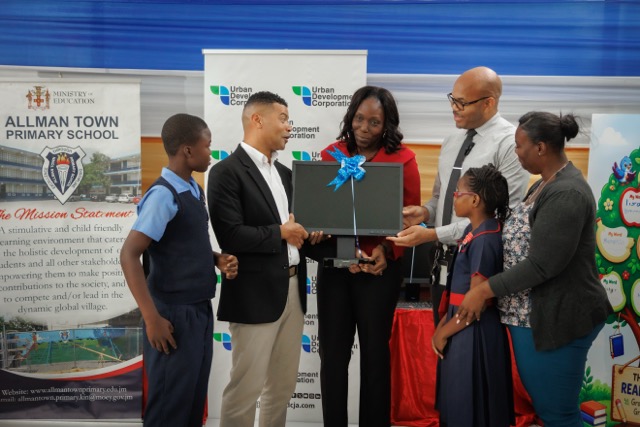 UDC Donates Computer Equipment At Read Across Jamaica Day
 
L- R- Adrian Chin, Deputy General Manager, Corporate Services, Urban Development Corporation presents a set of computer monitors to Thamar Russell-Brown, Acting Principal of the Allman Town Primary School on May 5, 2026 at the annual Read Across Jamaica day exercises. Joining in the occasion are Lucien Henry, Education Officer, Renee Campbell, Board Chairman and Yajaun Ainsworth, male student leader and Tashayne Johnson, female student leader. The UDC has a strong corporate social responsibility programme in select areas and also conducted reading exercises and computer equipment handovers in Montego Bay and Ocho Rios even as it sets its sights on Labour Day 2026. 